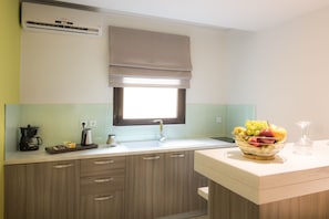 Una cocina con ventana, un fregadero, una cafetera y un frutero.