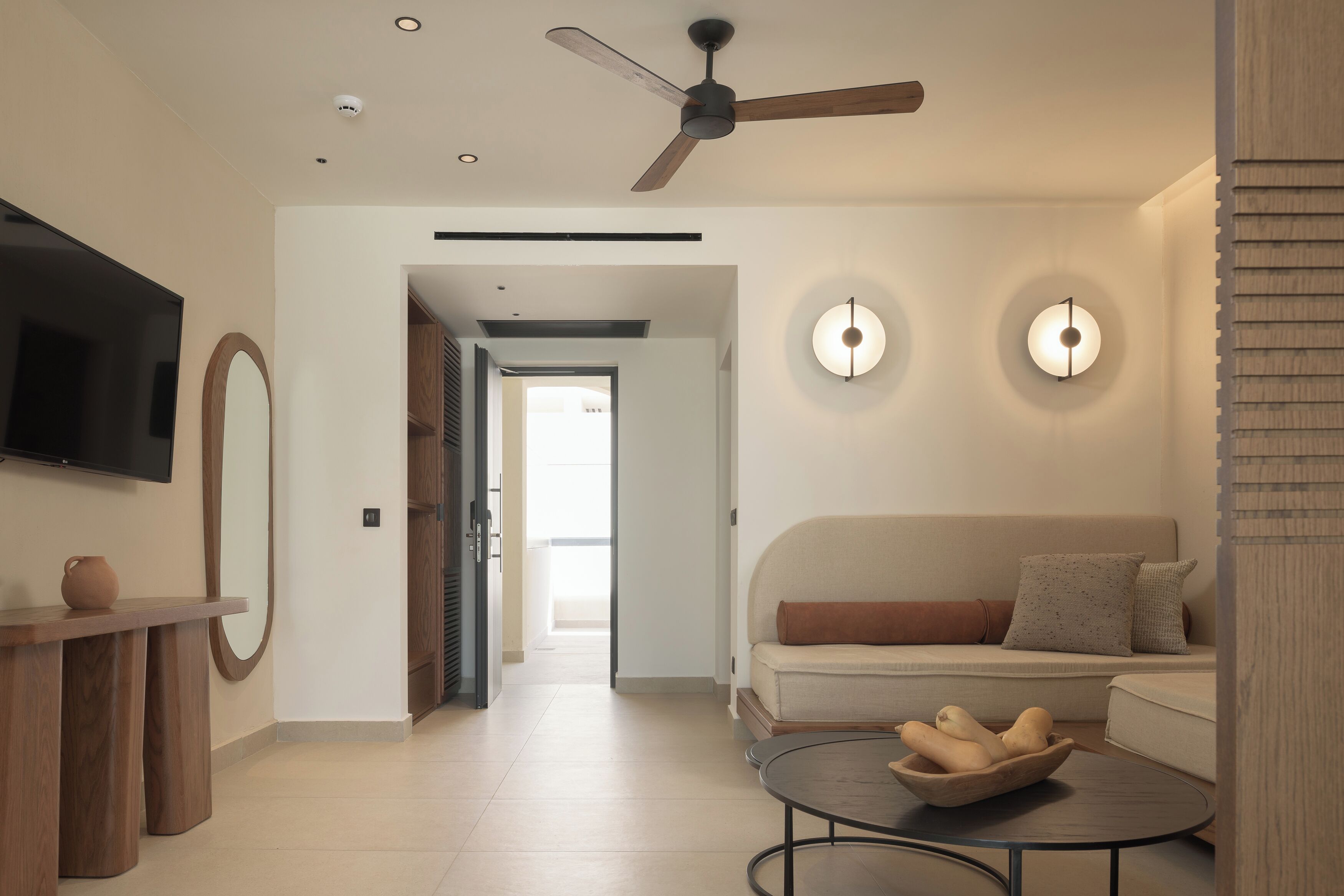 A modern living room with a sofa, a coffee table, a TV, and a ceiling fan.