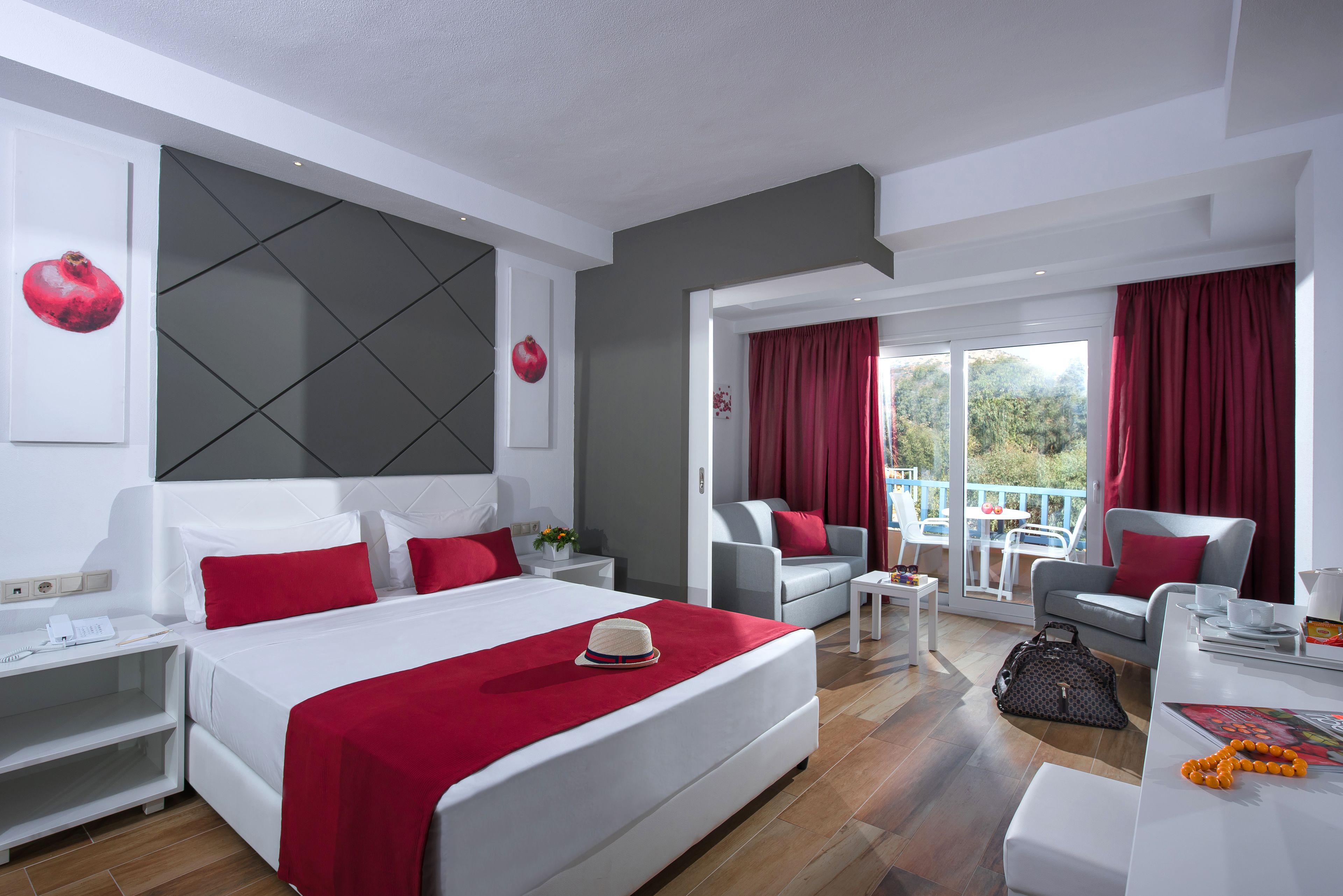 A modern hotel room with a large bed, a sofa, a dining table, and a balcony with red curtains.