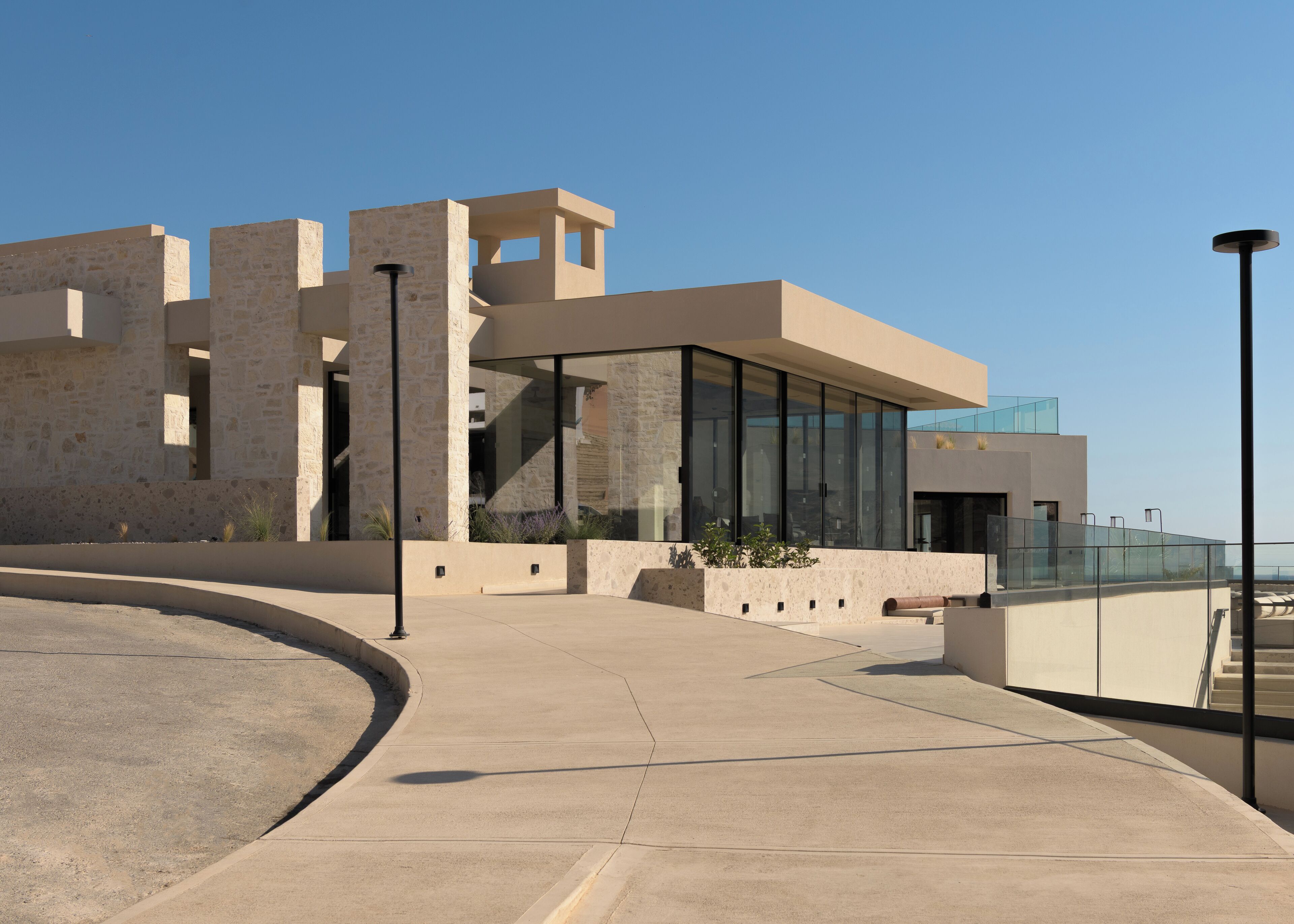 A modern building with a curved pathway, large glass windows, and stone walls.