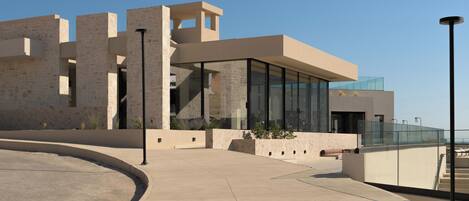 A modern building with a curved pathway, large glass windows, and stone walls.