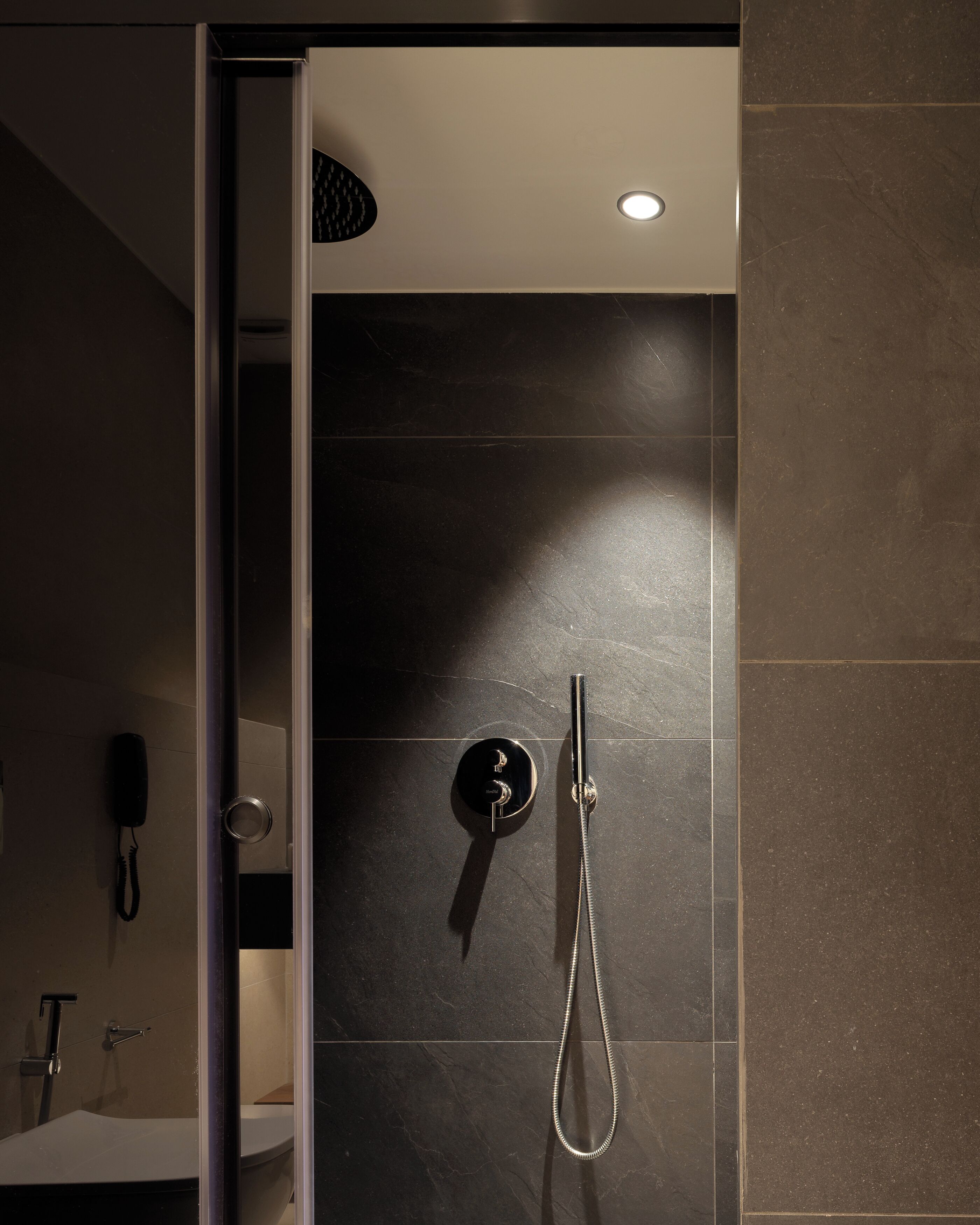 A modern bathroom with a shower, a toilet, and a sink.