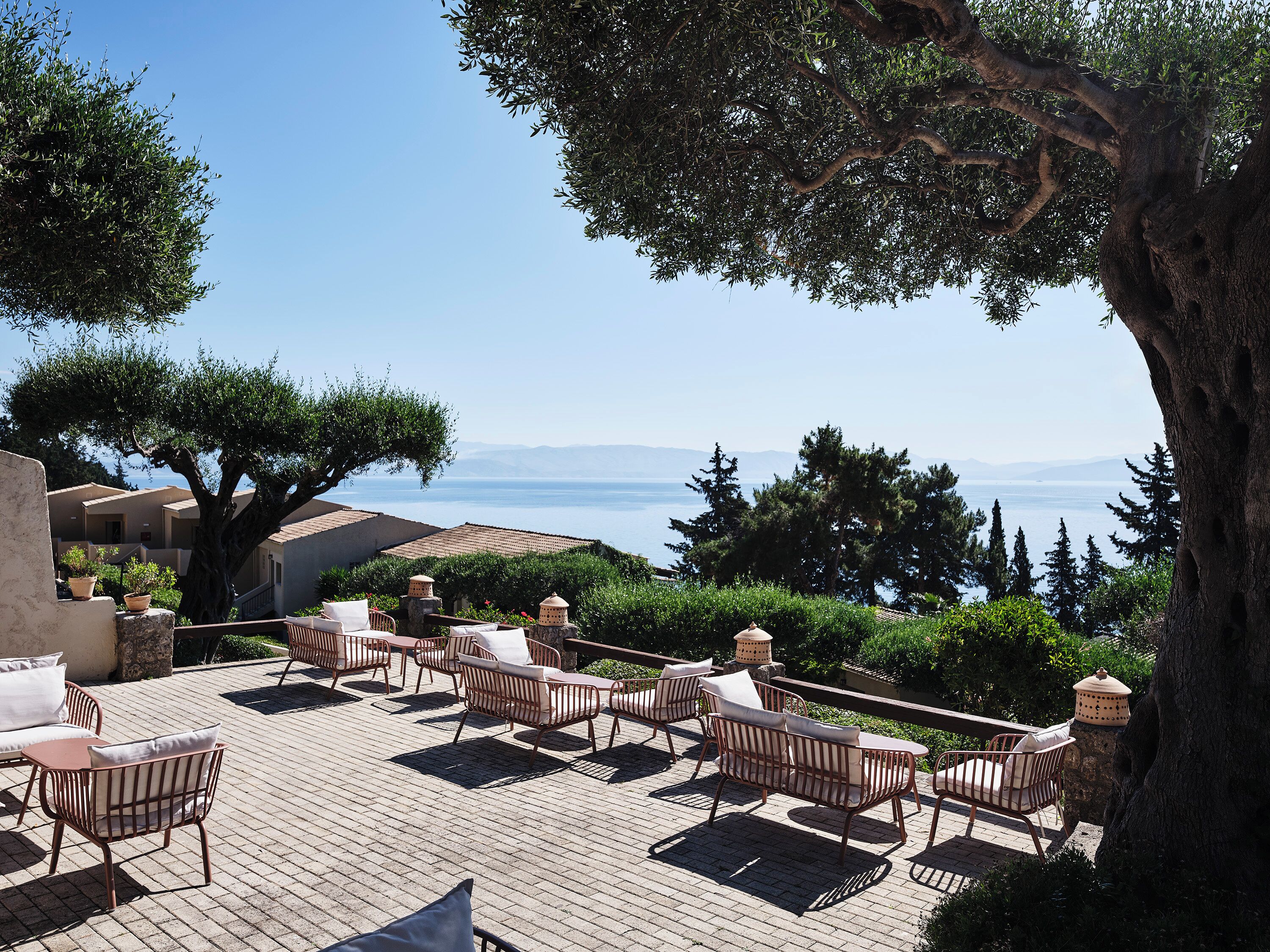 An outdoor seating area with wicker furniture and a view of the sea.