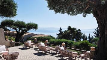 An outdoor seating area with wicker furniture and a view of the sea.