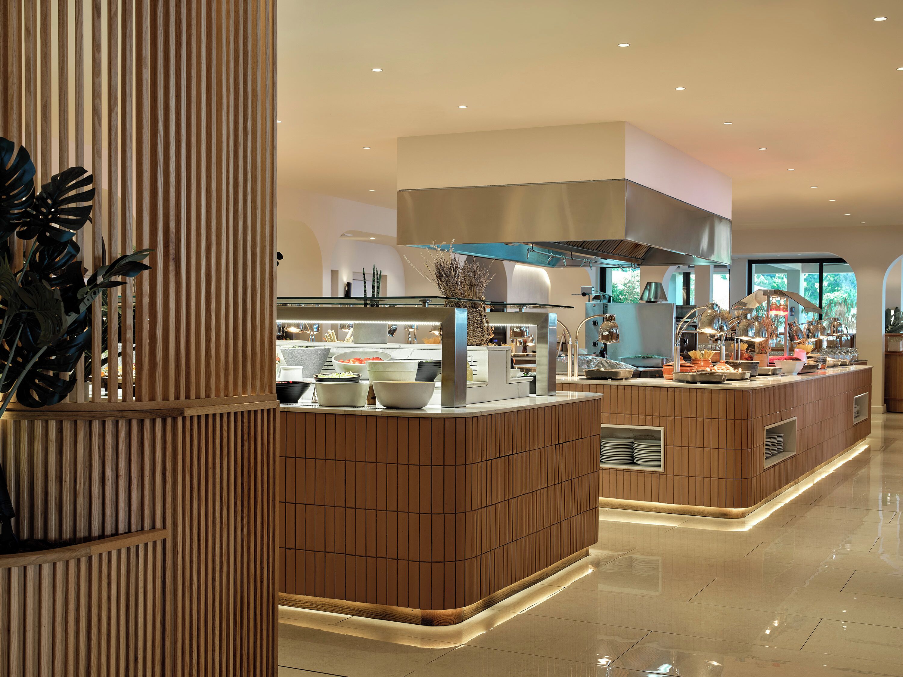A modern kitchen with a central island, wooden paneling, and stainless steel appliances.