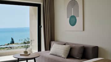 A modern room with a sofa, a small round table, and a view of the sea.