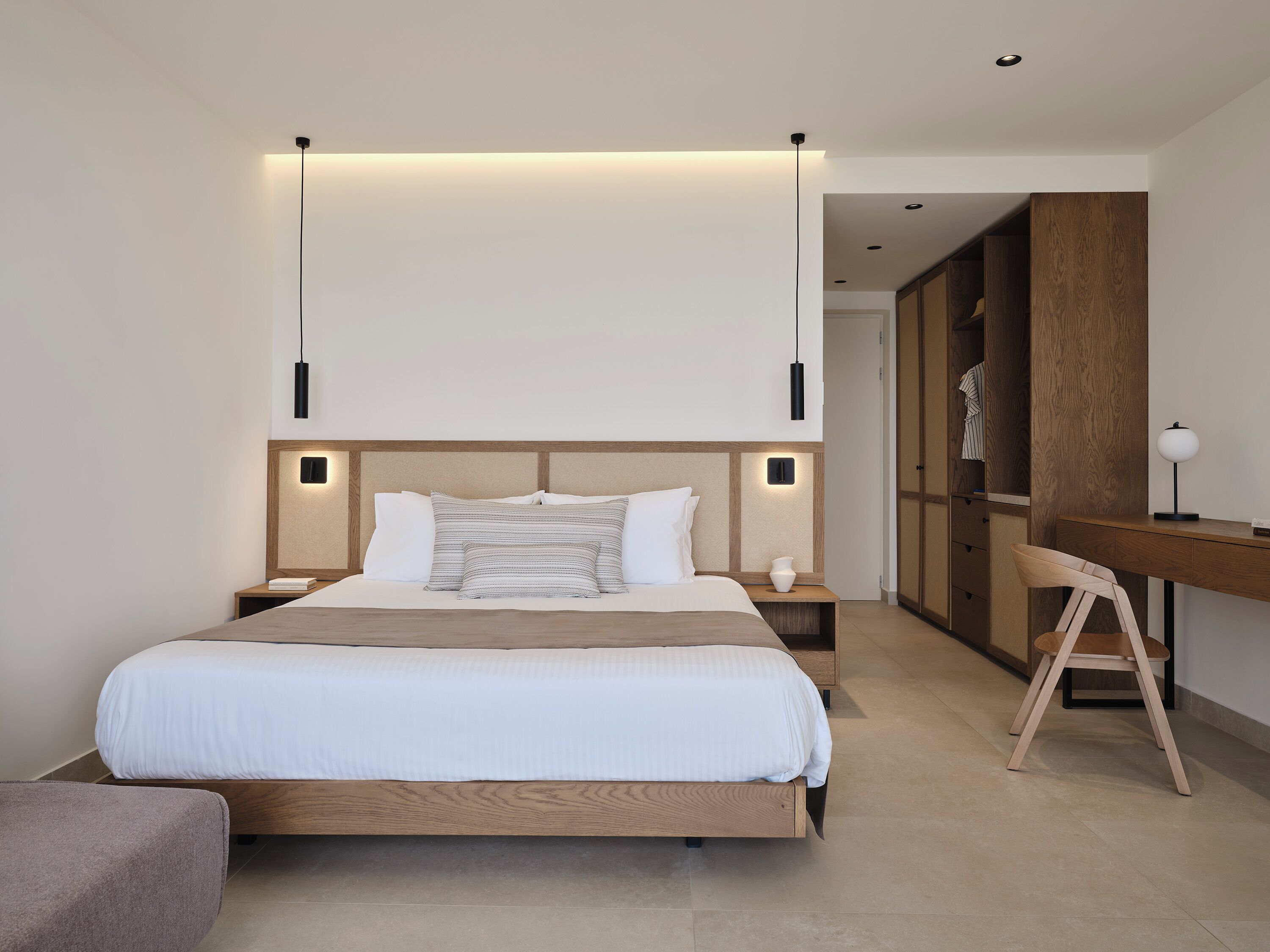 Un dormitorio moderno con una cama grande, mesitas de noche, un escritorio y una silla.
