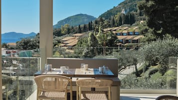 A terrace with a table set for two, overlooking a scenic hillside with houses and trees.