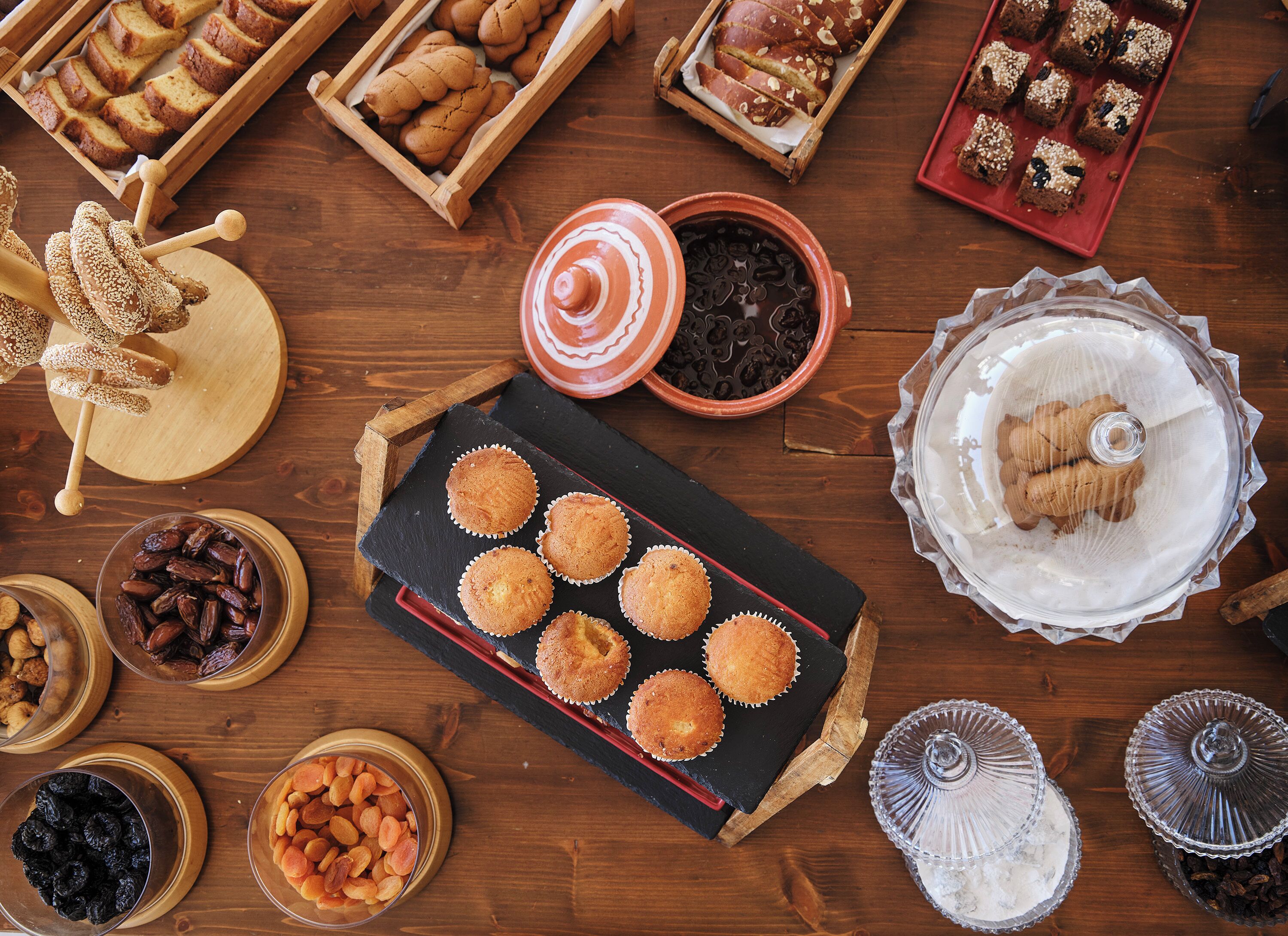 A wooden table with various baked goods, including muffins, cookies, and bread, arranged on a tray.