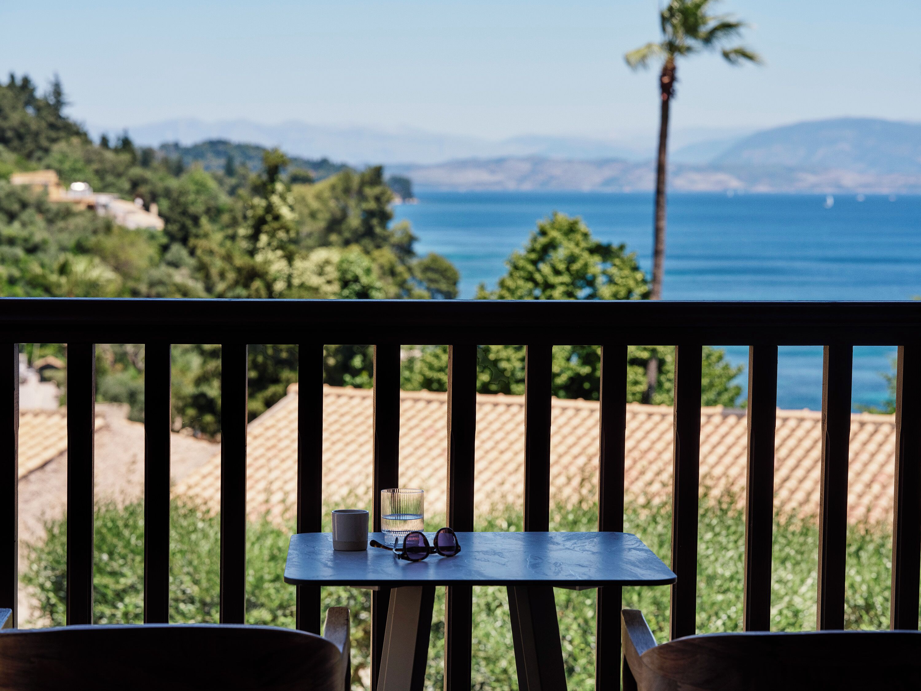 A balcony with a table, a glass, and a pair of glasses.
