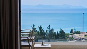 Una habitación con una mesa y sillas cerca de una ventana que da a una masa de agua y montañas al fondo.
