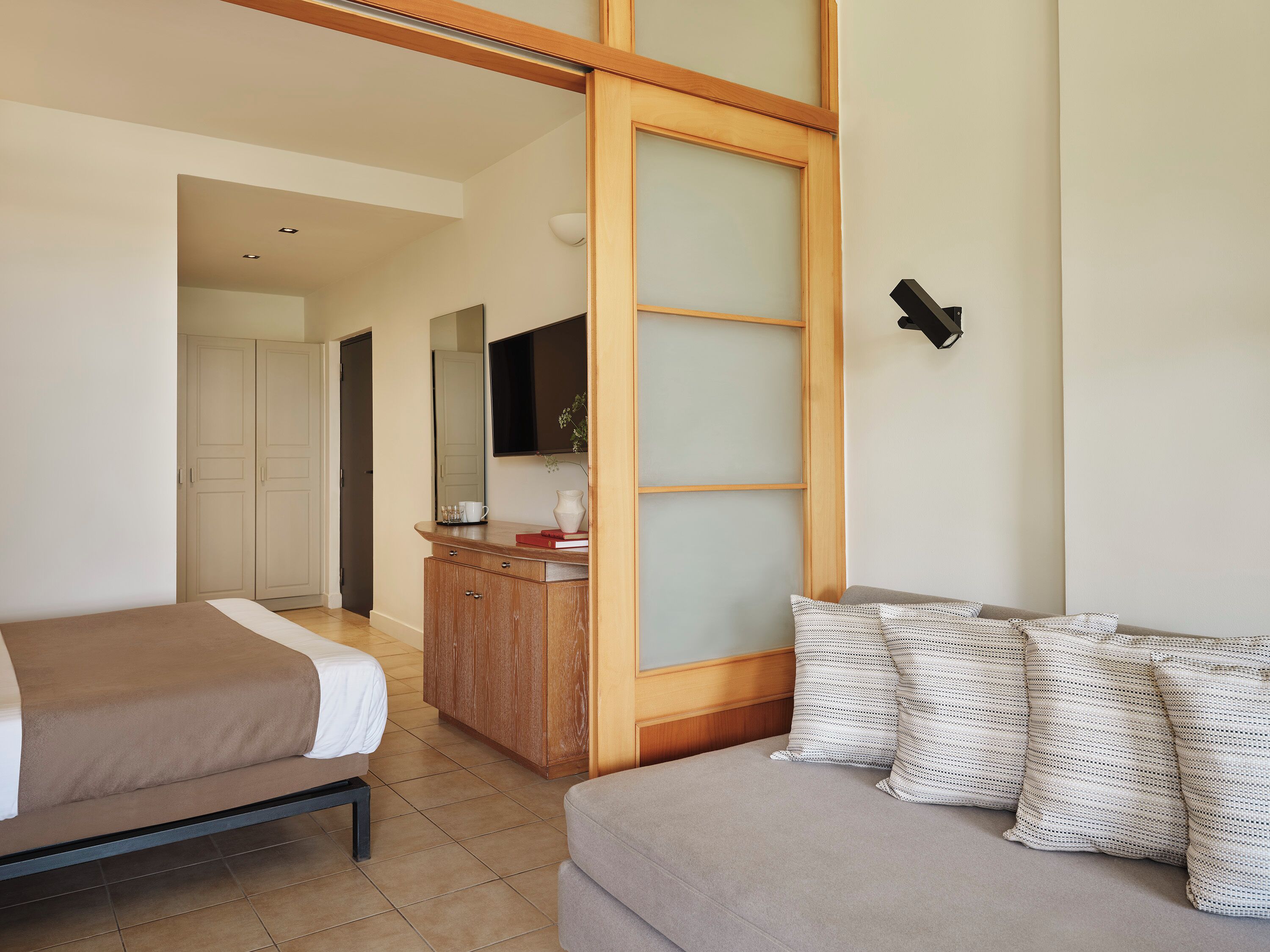Una habitación de hotel con cama, sofá, aparador de madera y espejo.