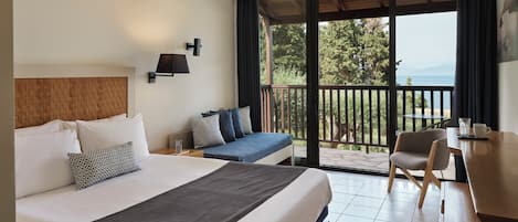 Habitación de hotel con una cama grande, un escritorio y un balcón con vistas.