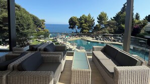 Un espacio de estar al aire libre cubierto con muebles de mimbre, piscina y vistas al mar.