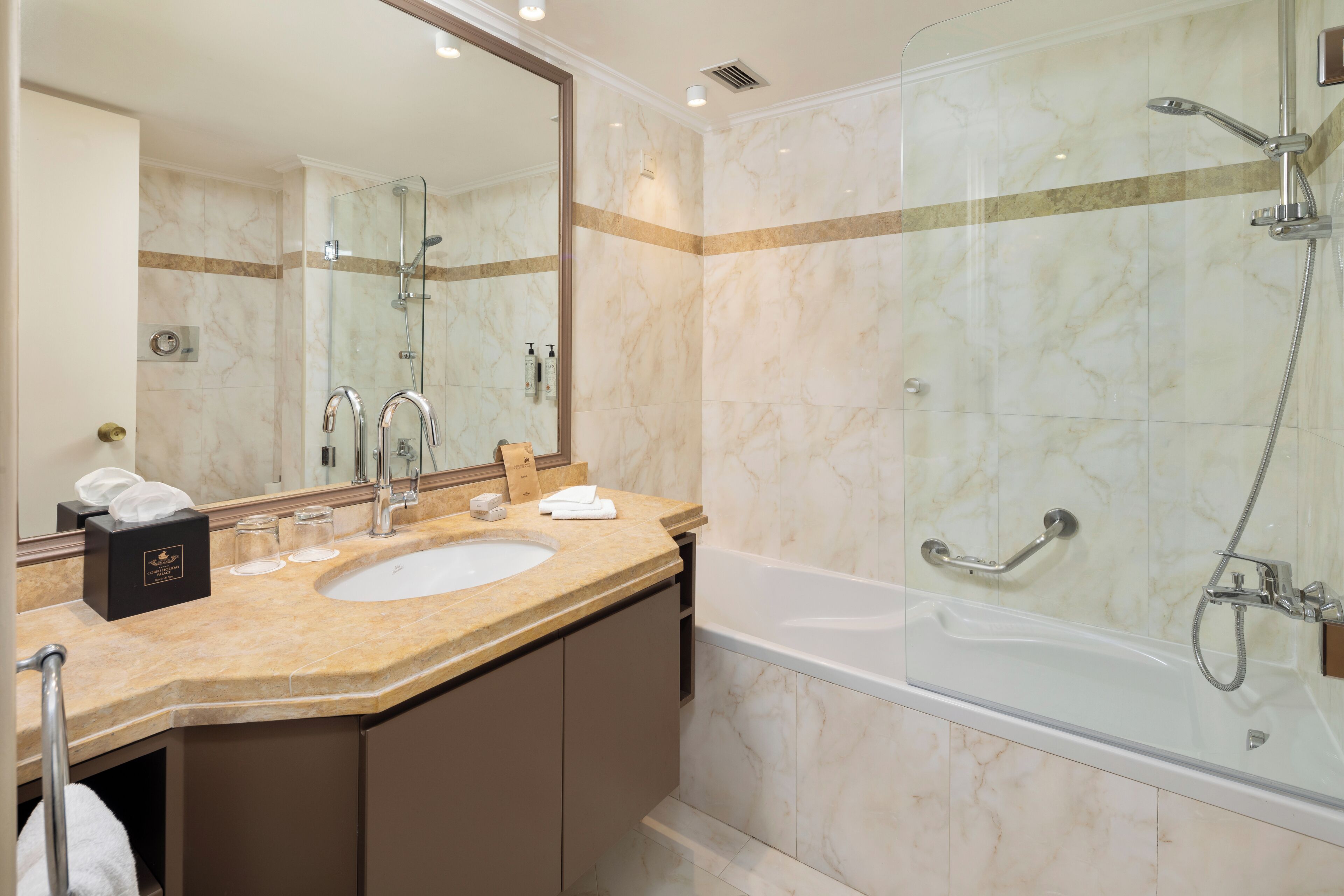 A modern bathroom with a marble sink, a large mirror, a glass-enclosed shower, and a bathtub.
