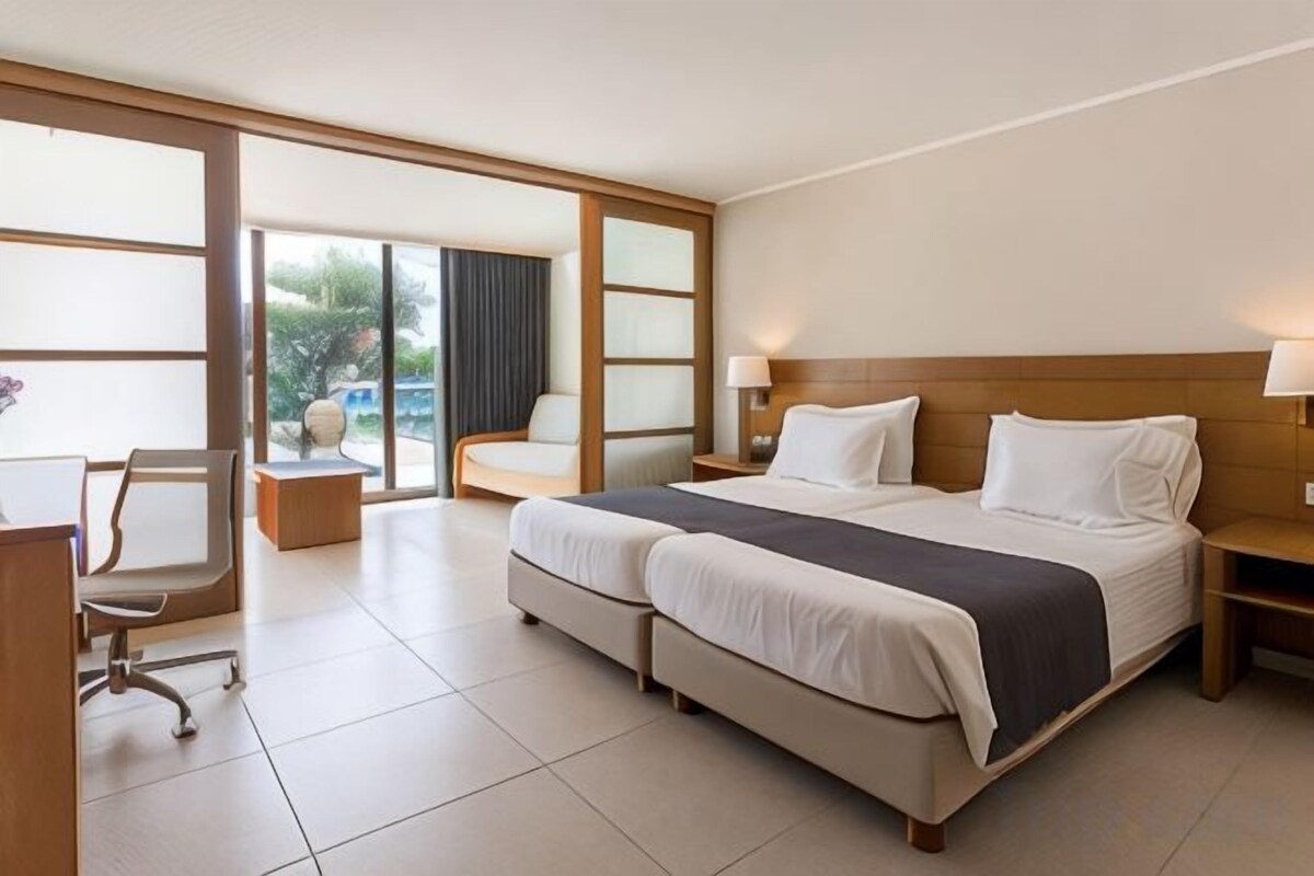 Habitación de hotel con cama doble, escritorio, silla y vistas al exterior.