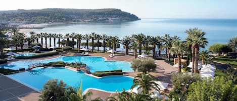Una piscina al aire libre, una piscina infinita, sombrillas