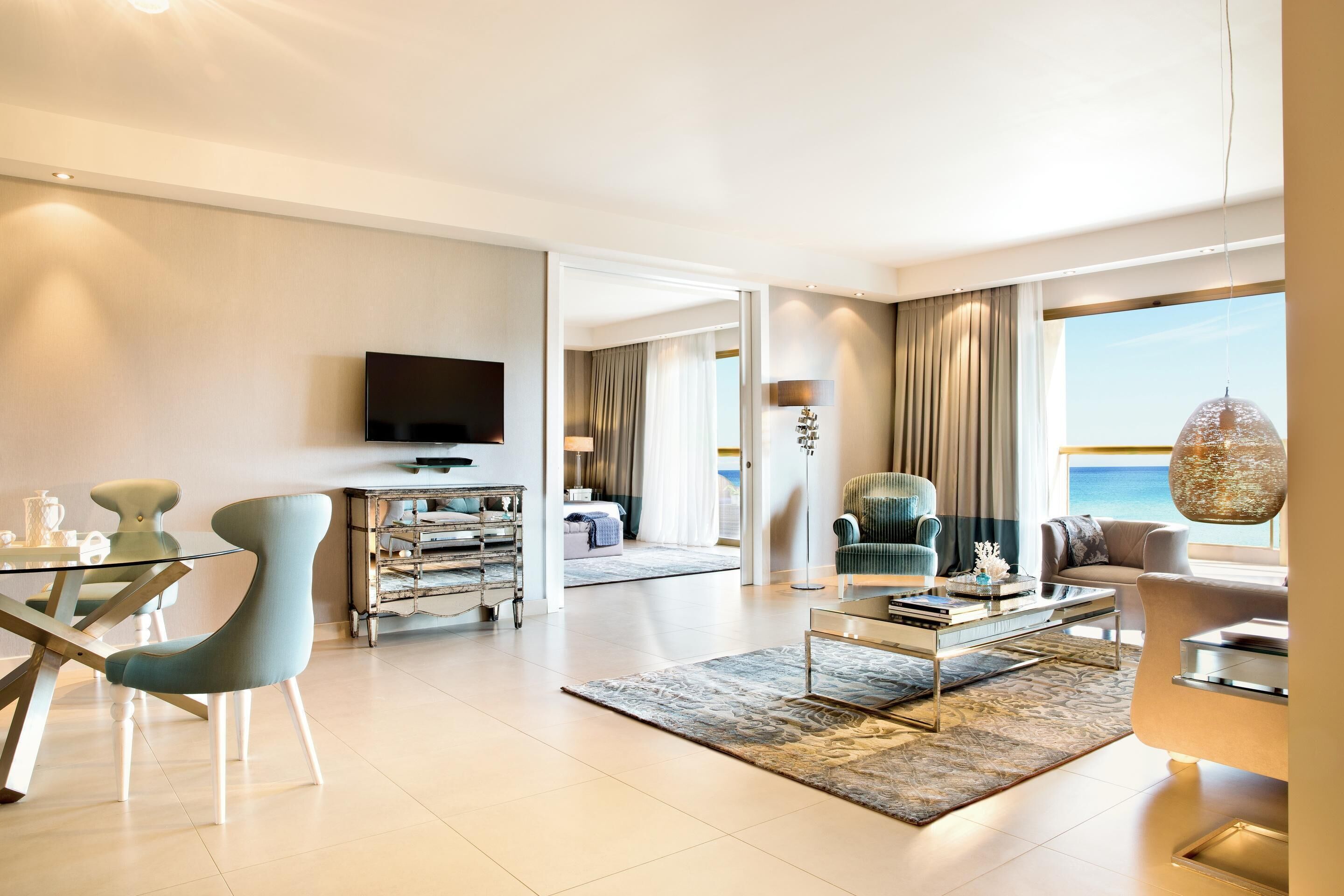 A modern living room with a glass coffee table, a sofa, and a television.