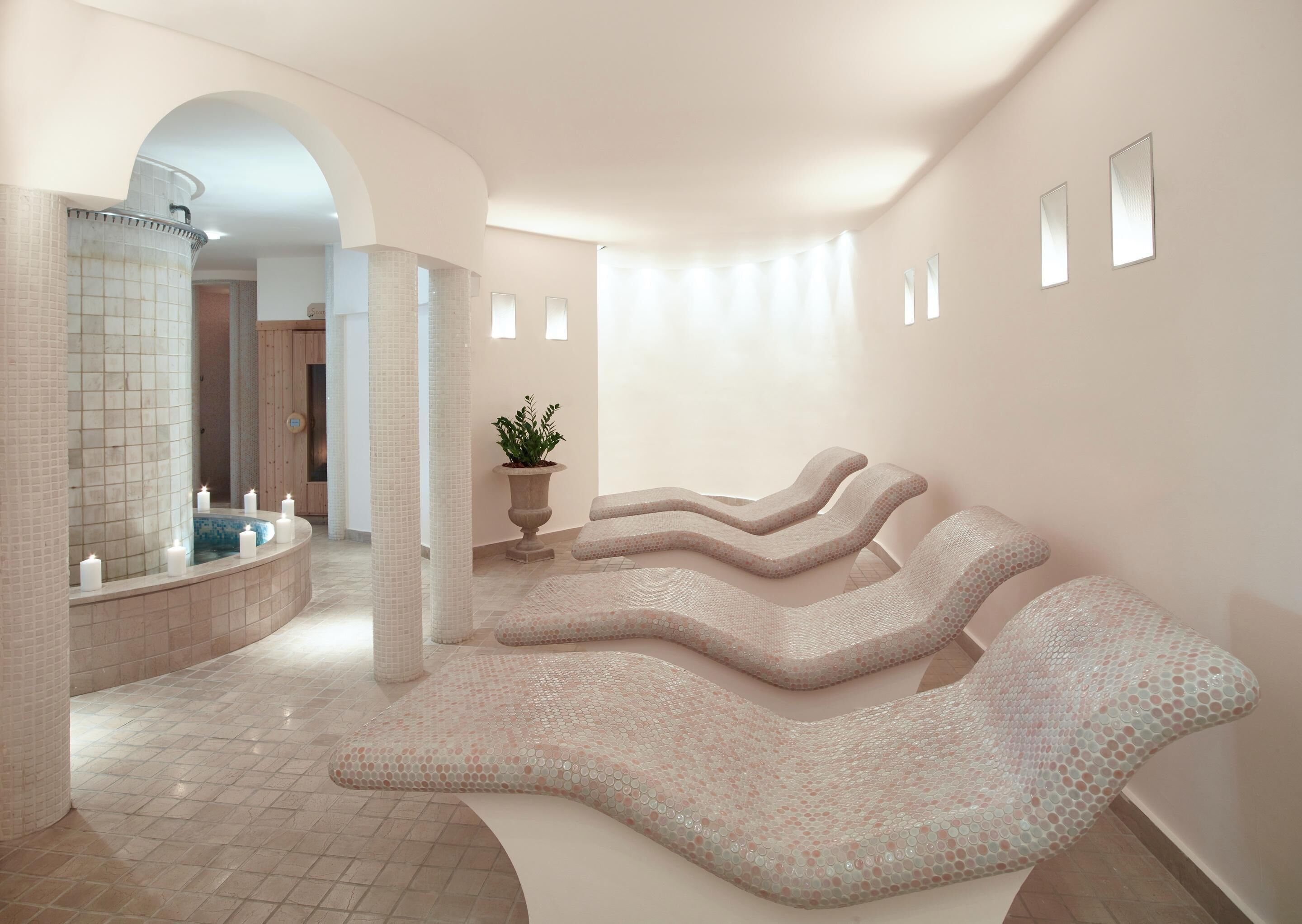 A spa area with a curved seating area, a small fountain, and a potted plant.