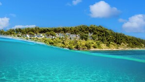 A coastal resort with beachfront villas, clear turquoise waters, and lush greenery.