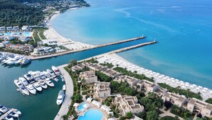 An aerial view of a coastal resort with a marina, beach, and hotel buildings.