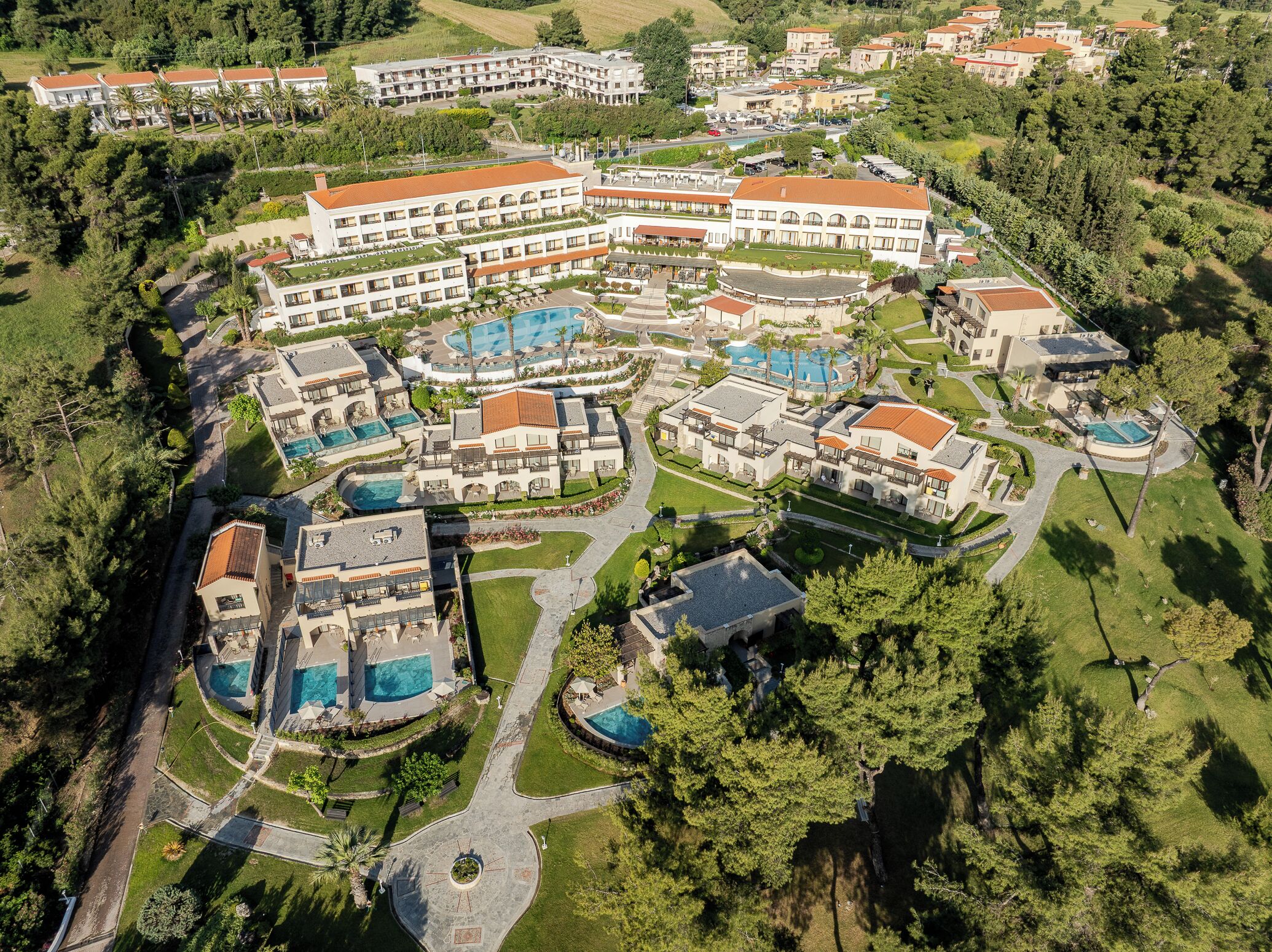 An aerial view of a resort with multiple buildings, swimming pools, and landscaped areas.