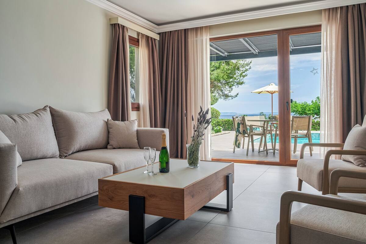 Un salon moderne avec un canapé, une table basse et une vue sur un espace piscine extérieur.