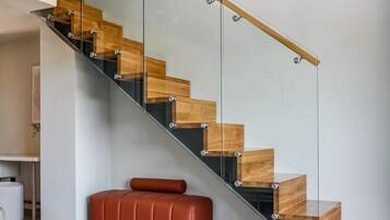 Un intérieur moderne avec un escalier en verre, un banc en cuir et une table avec des magazines.