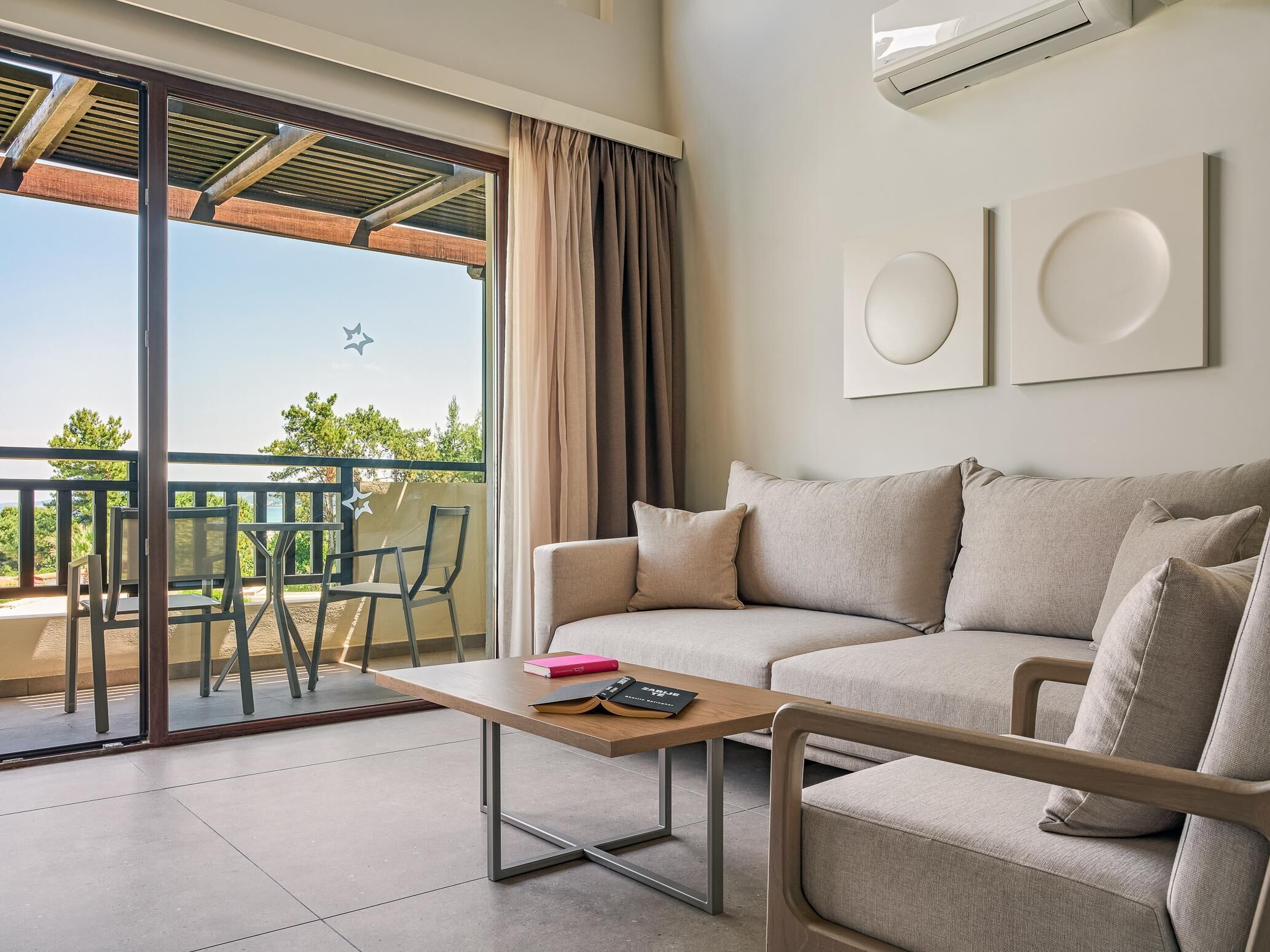 A modern living room with a sofa, a coffee table, and a balcony with a table and chairs.