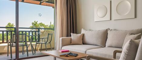 A modern living room with a sofa, a coffee table, and a balcony with a table and chairs.