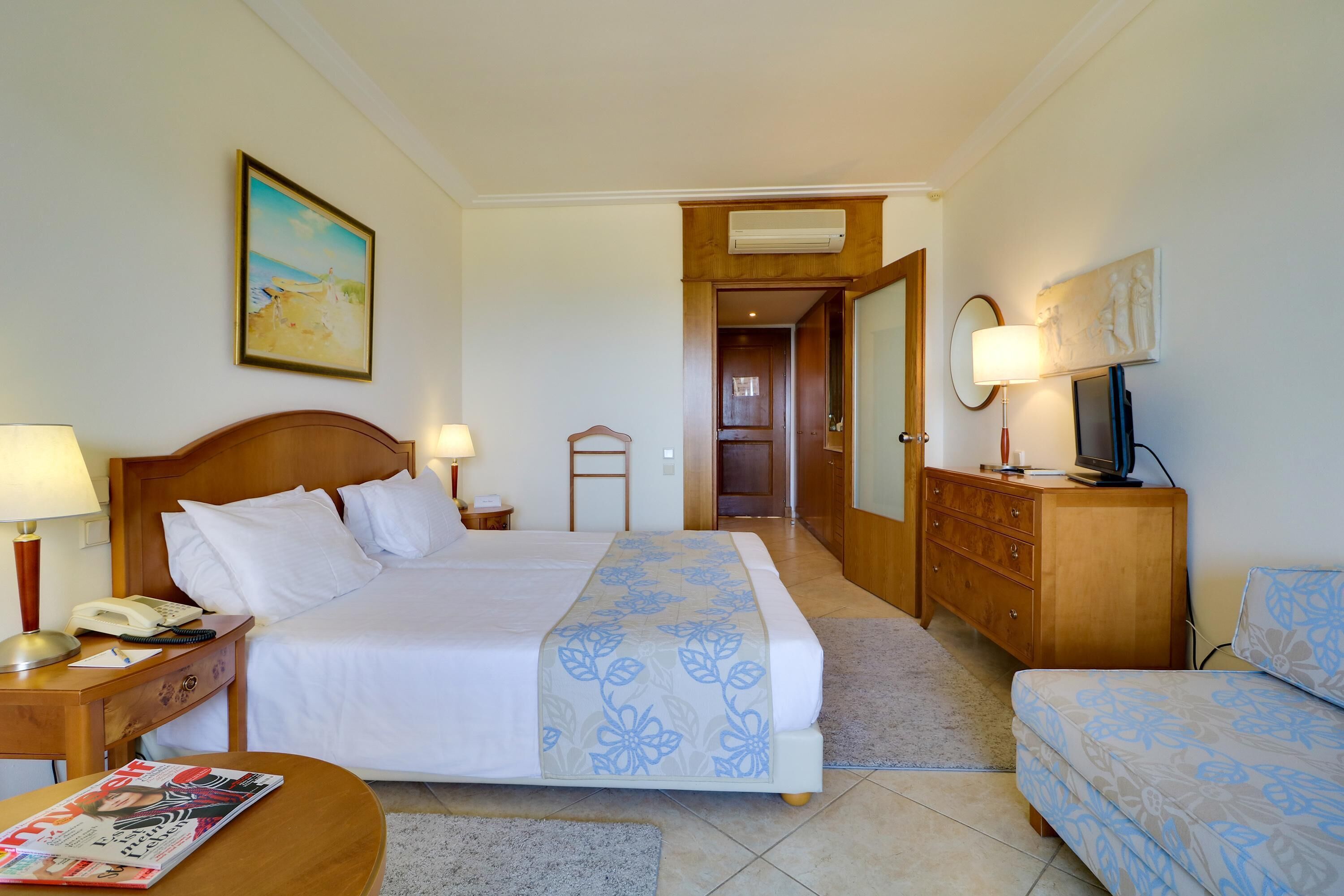 Une chambre d’hôtel avec un lit, une table de chevet, une lampe et un magazine posé sur une petite table.