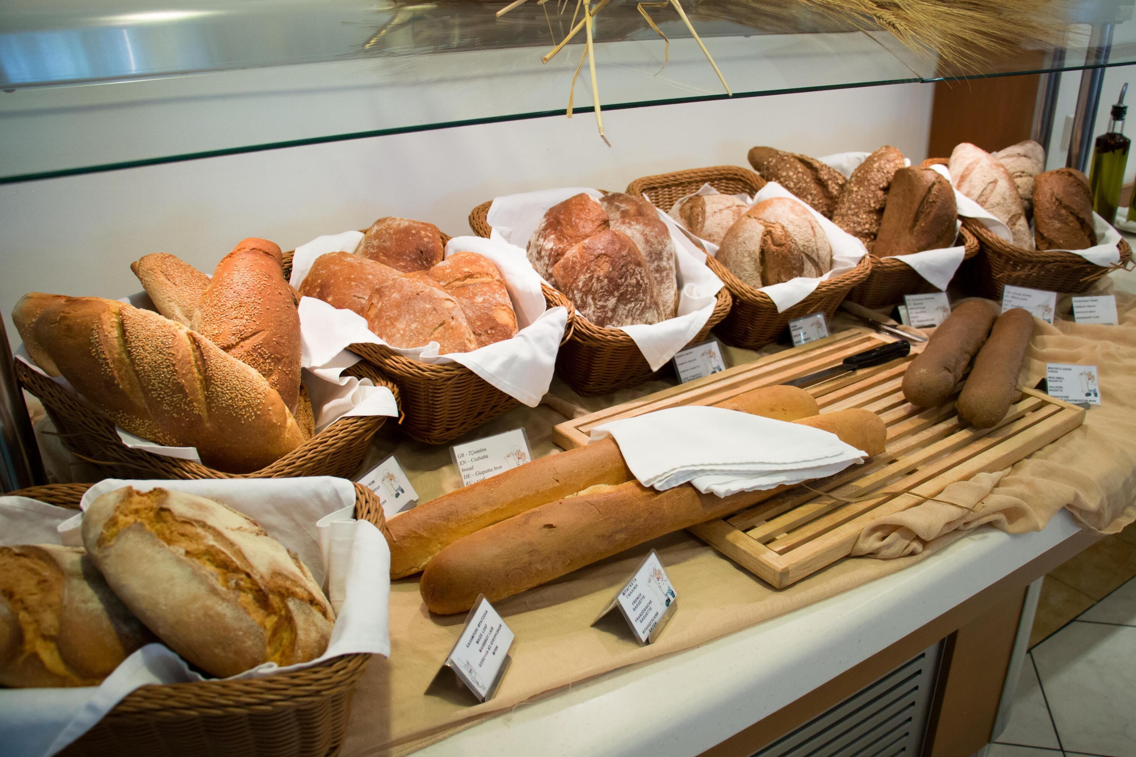 A bakery display with various types of bread in baskets and on a wooden board.