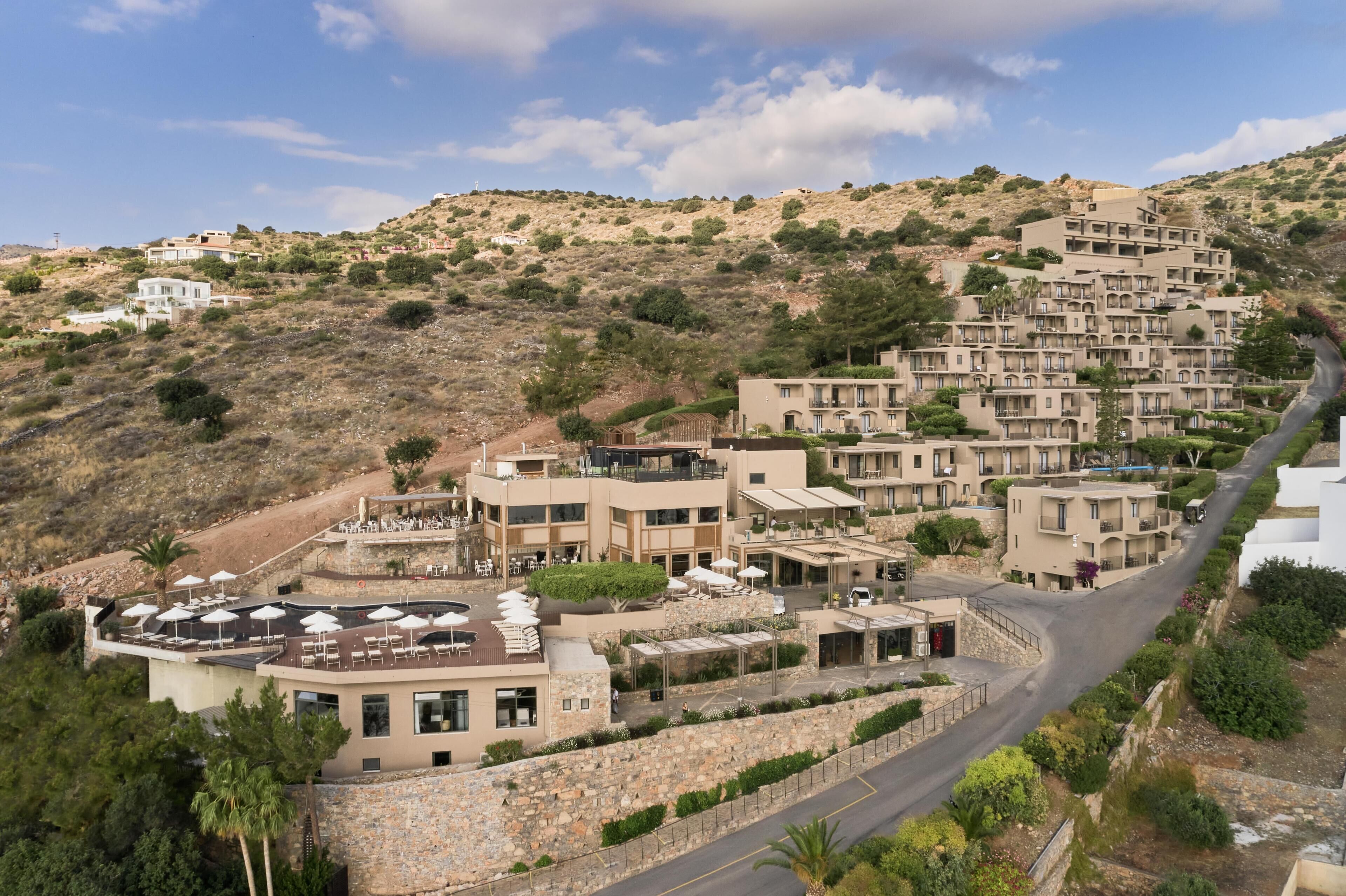 Un quartier résidentiel situé sur une colline, avec des immeubles à plusieurs étages, une route sinueuse et des espaces aménagés pour se détendre en plein air.