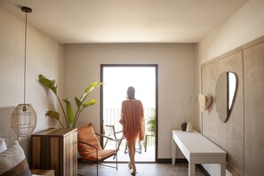 Habitación moderna con un ventanal grande, una mesita de madera, un banco blanco y una lámpara colgante.