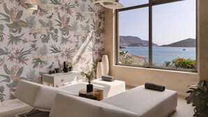Una habitación moderna con un ventanal grande, un sofá blanco, una mesita de madera y una planta decorativa.