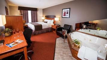 Una habitación de hotel con cama, escritorio, silla, mesita de noche, lámpara y bañera.