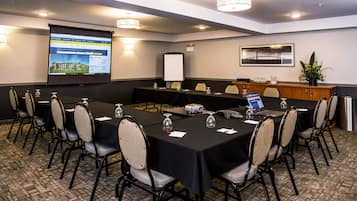 A conference room with a projector screen displaying a presentation, a whiteboard, and a laptop on a table.