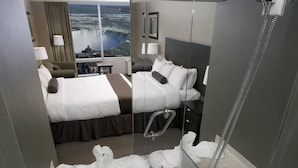 A hotel room with a large bathtub, a shower, and a bed with a view of a waterfall.