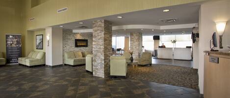 A spacious lobby with a high ceiling, stone pillars, and a reception desk.