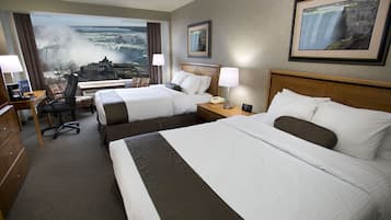 A hotel room with two beds, a desk, a chair, and a view of a waterfall.