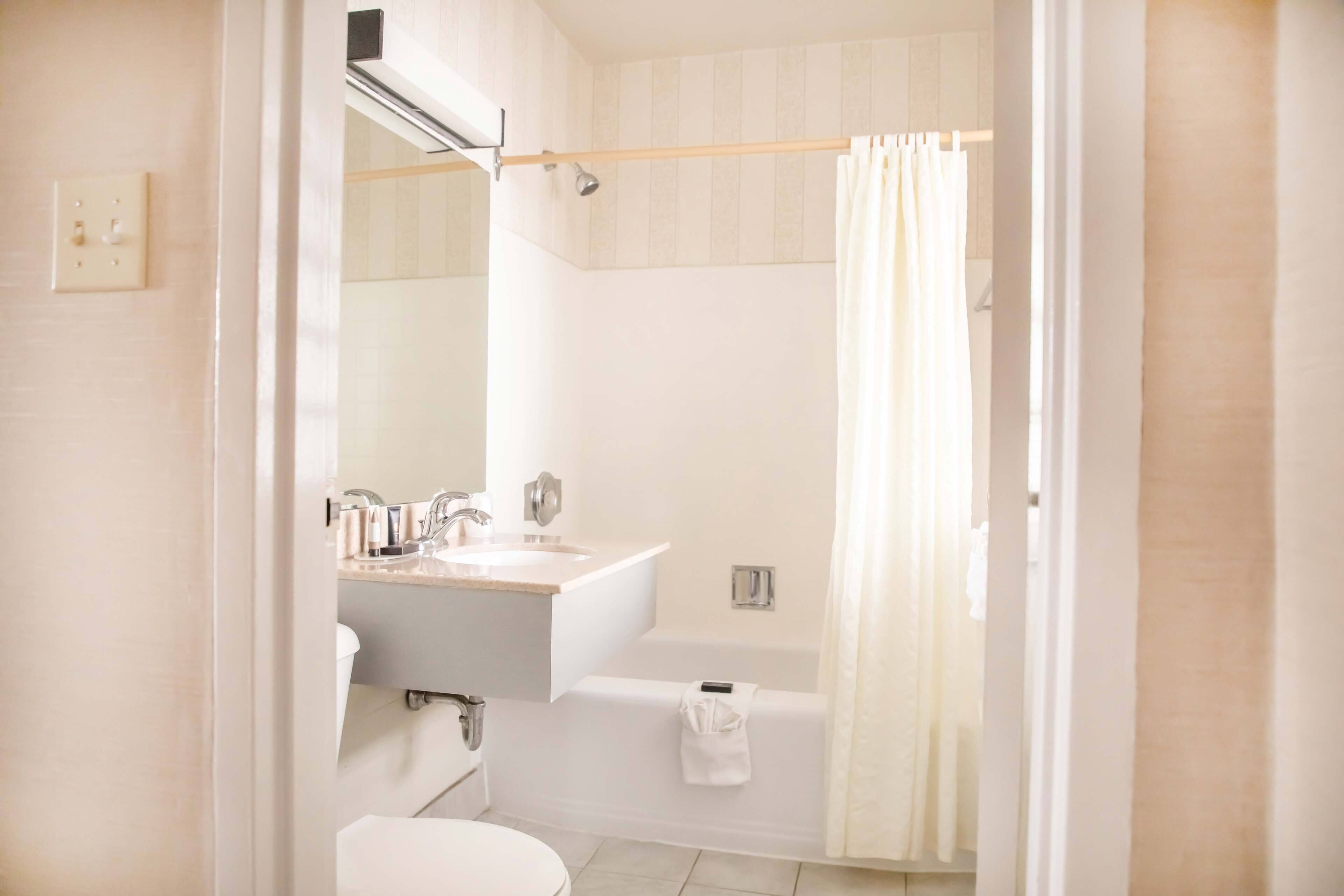 A bathroom with a sink, mirror, and bathtub.