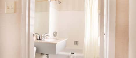 A bathroom with a sink, mirror, and bathtub.