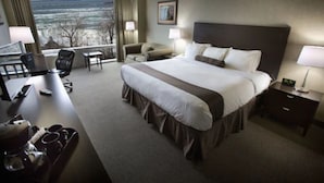 A hotel room with a large bed, a desk with a computer, a chair, and a view of the outdoors.