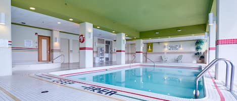 An indoor swimming pool with clear safety signage, a tiled floor, and a green ceiling.