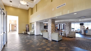 A spacious lobby with a high ceiling, stone pillars, and multiple seating areas.