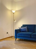 A room with a blue sofa, a floor lamp, and a wooden floor.