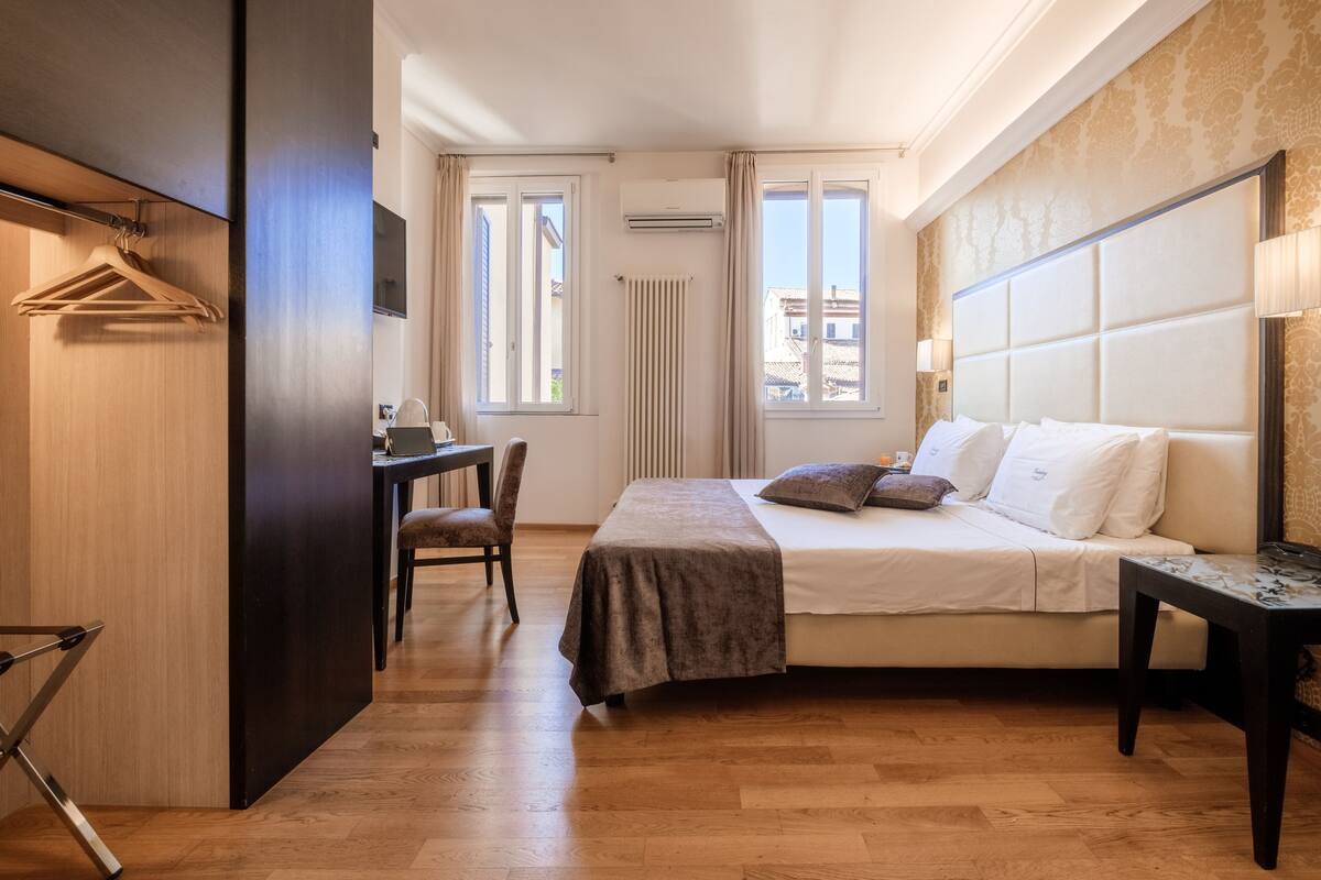 A bedroom with a bed, bedside table, chair, and a desk with a chair.