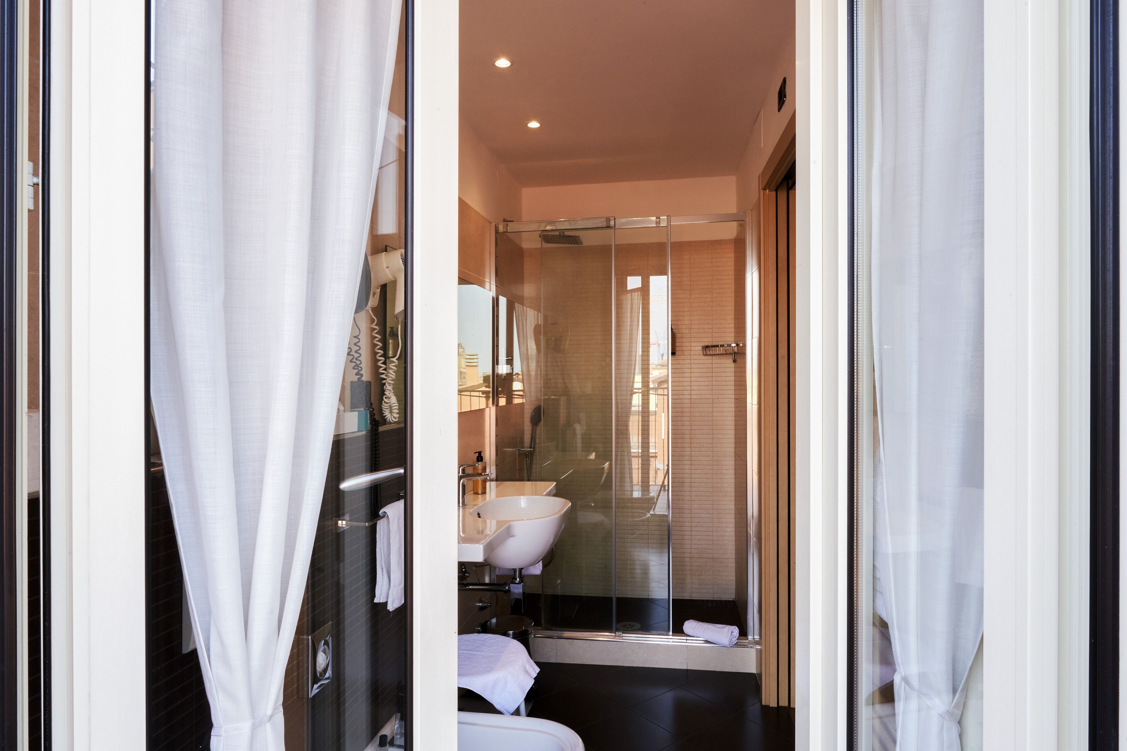 Une salle de bain moderne avec une douche à l’italienne en verre, un lavabo blanc et une baignoire.