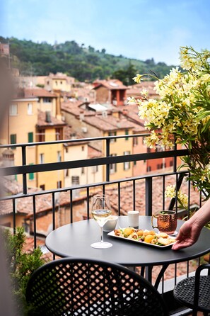 A balcony with a table set for a meal, a glass of white wine, and a copper mug. - Touring Hotel (Bologna)