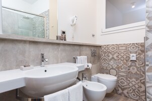 Een moderne badkamer met een groot wastafel, toilet, bidet en een douche met glazen wanden.